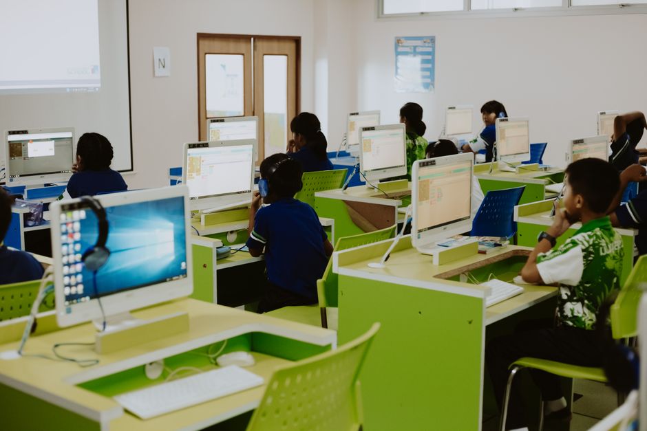 Grupo reducido de alumnos trabajando con ordenadores en un aula.